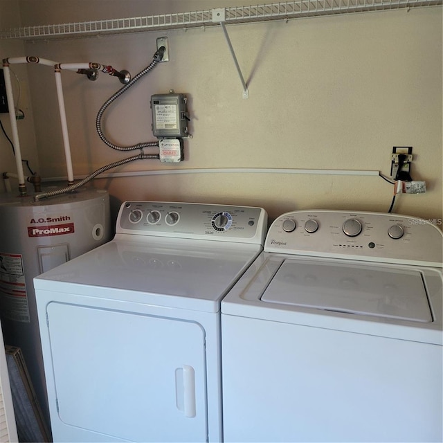 washroom with water heater, washing machine and clothes dryer, and laundry area