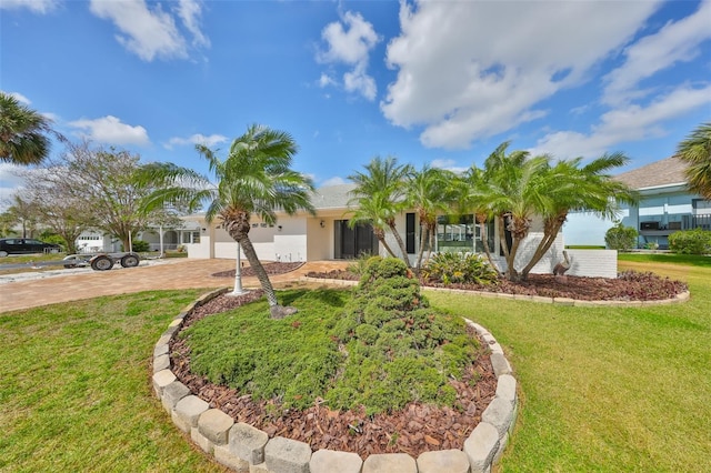 ranch-style home featuring driveway, a front yard, a garage, and stucco siding