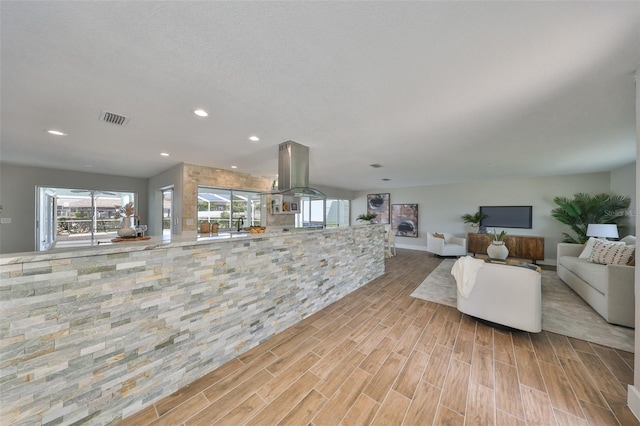 living room featuring light wood-type flooring, plenty of natural light, recessed lighting, and visible vents