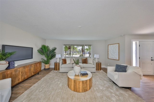 living room featuring baseboards, a textured ceiling, and wood finished floors