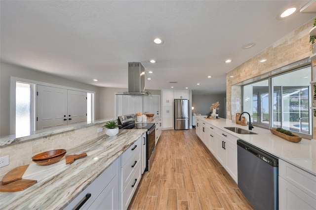 kitchen featuring white cabinets, stainless steel appliances, a sink, island range hood, and light wood-type flooring