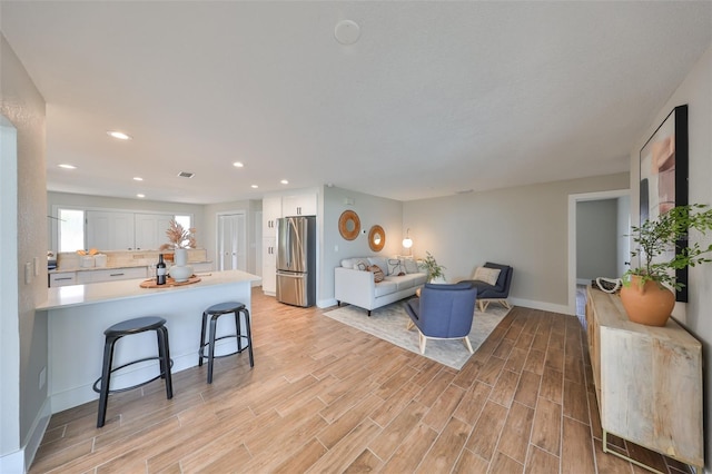 living room featuring baseboards, light wood-style flooring, and recessed lighting