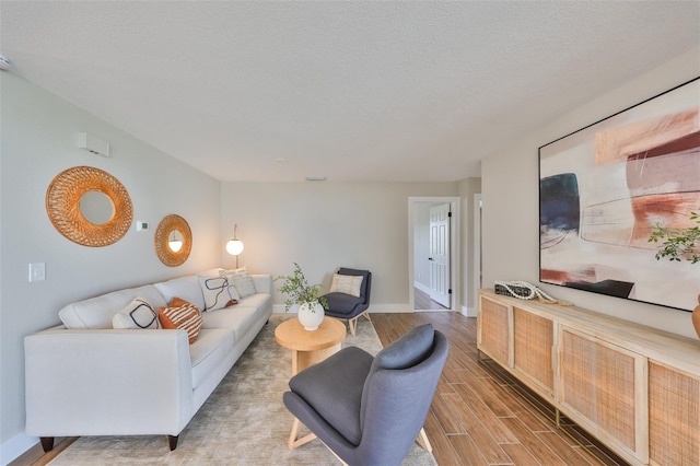 living room with a textured ceiling, baseboards, and wood finish floors