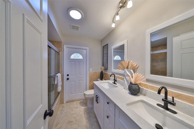 bathroom with a sink, tile walls, and an enclosed shower