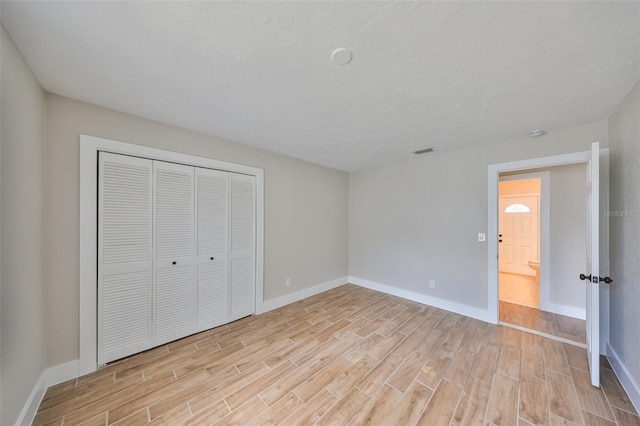 unfurnished bedroom featuring a closet, baseboards, and light wood-style floors