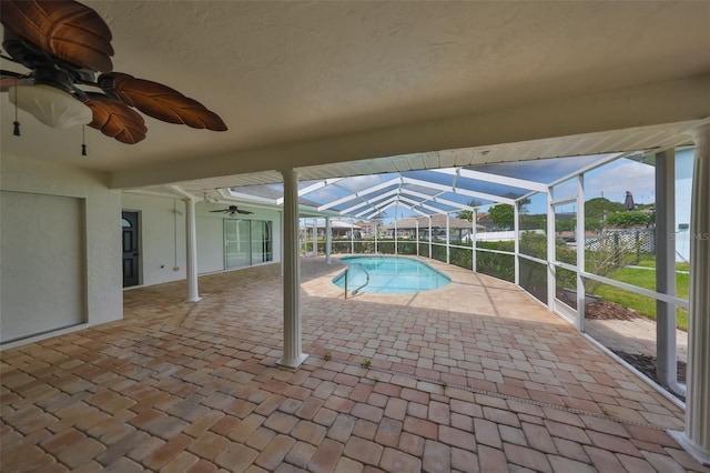 outdoor pool with glass enclosure, ceiling fan, and a patio