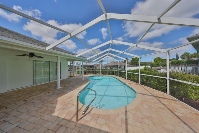 outdoor pool with a patio, a ceiling fan, and glass enclosure