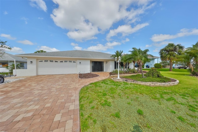 ranch-style house with decorative driveway, a front yard, and an attached garage