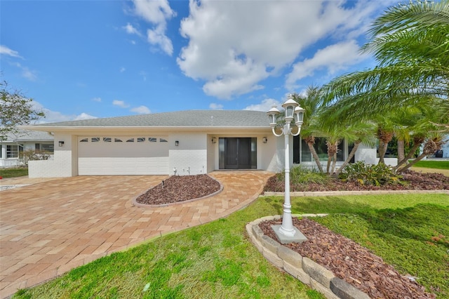 single story home featuring an attached garage, brick siding, and decorative driveway