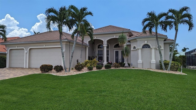 mediterranean / spanish-style house with a tiled roof, a garage, stucco siding, and a front lawn