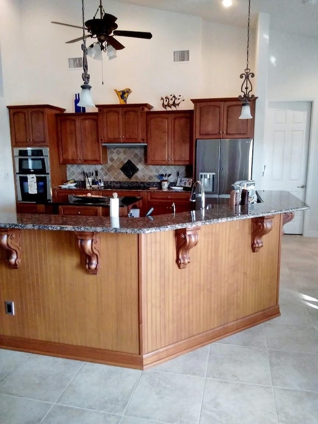 kitchen featuring visible vents, a breakfast bar, ceiling fan, and stainless steel appliances