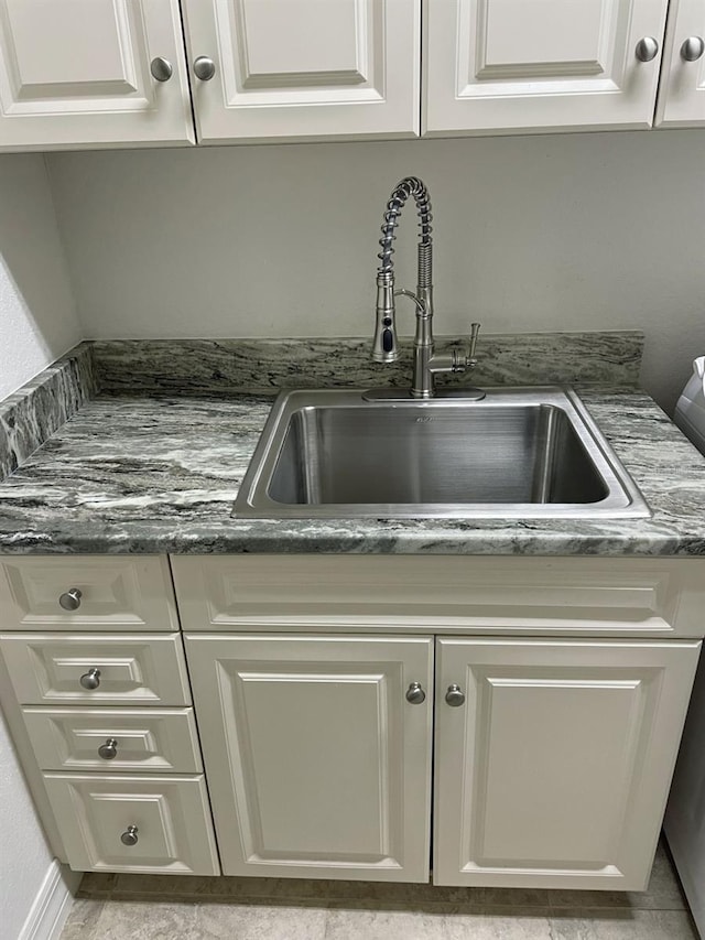 details with dark stone counters, white cabinets, and a sink