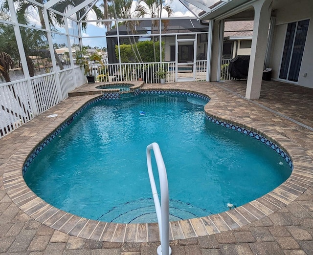 view of swimming pool with glass enclosure, a pool with connected hot tub, and a patio