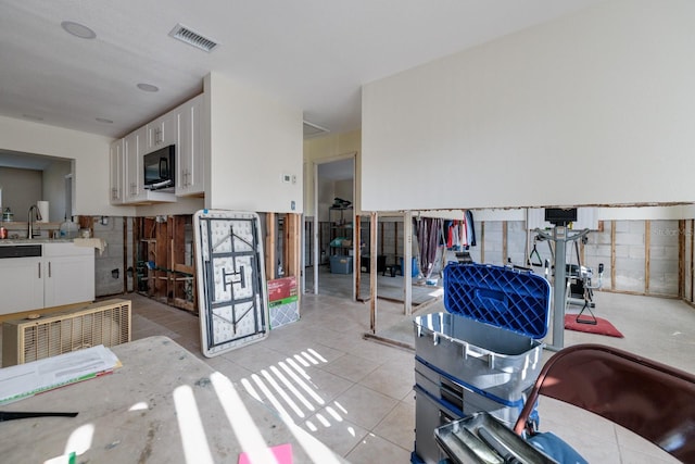4126 Carson St NE, Saint Petersburg, FL 33703 - interior space with visible vents, black microwave, white cabinetry, and light tile patterned floors