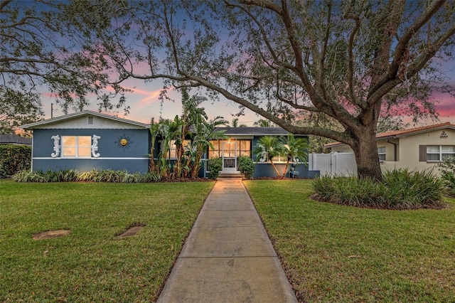 view of front of house with a front yard, a gate, stucco siding, and fence