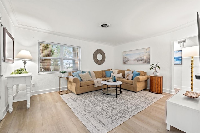 living area featuring baseboards, crown molding, visible vents, and light wood-type flooring