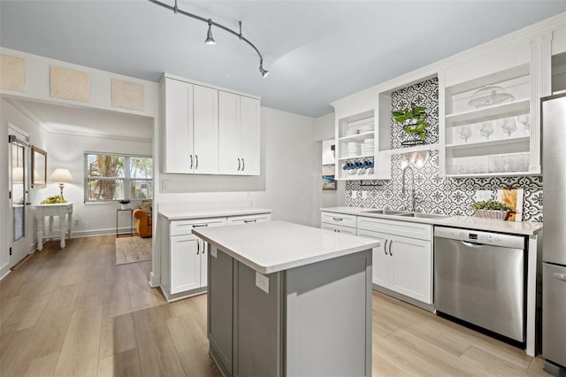 kitchen featuring light countertops, a sink, open shelves, light wood finished floors, and stainless steel dishwasher