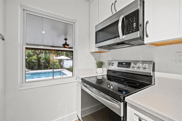 kitchen featuring white cabinets, light stone counters, and stainless steel appliances