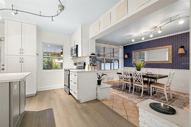 kitchen featuring white cabinetry, light countertops, rail lighting, light wood-type flooring, and appliances with stainless steel finishes