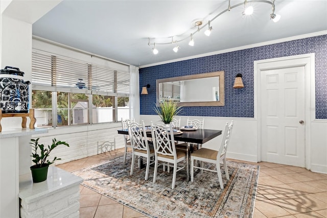 dining room with a wainscoted wall, wallpapered walls, tile patterned flooring, and crown molding