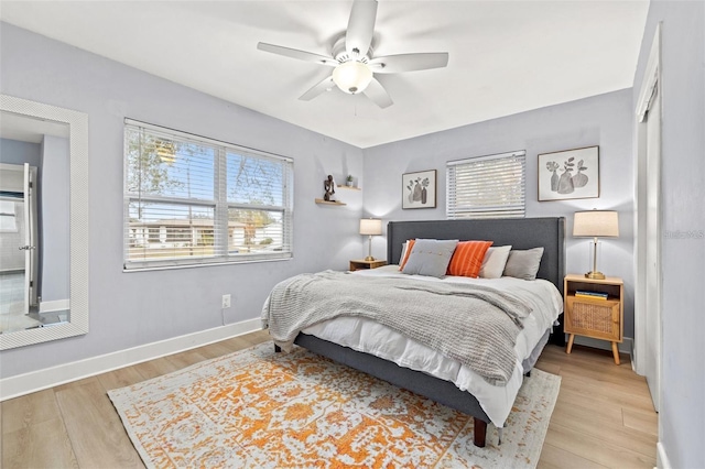 bedroom with light wood finished floors, multiple windows, and baseboards