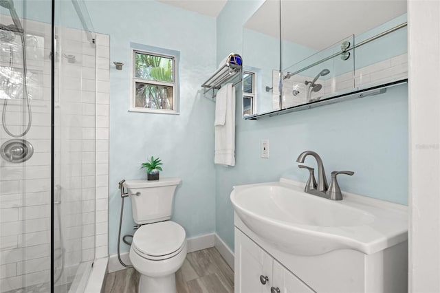 bathroom featuring a shower stall, baseboards, toilet, wood finished floors, and vanity