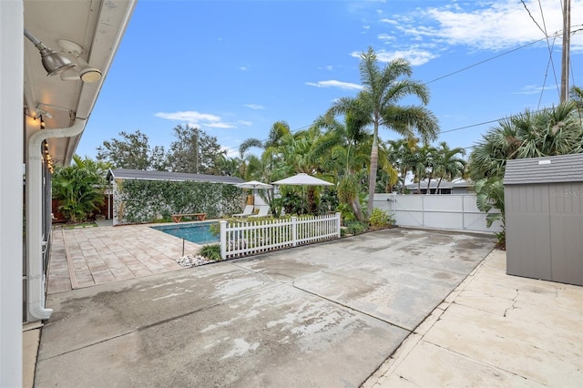 view of patio / terrace with an outbuilding, fence, and a fenced in pool