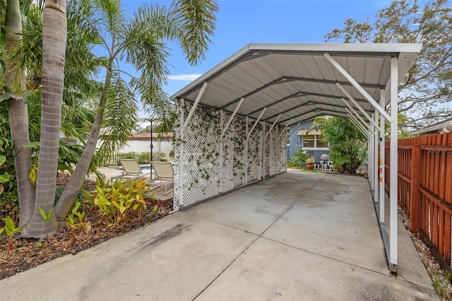 view of parking / parking lot with driveway, a carport, and fence