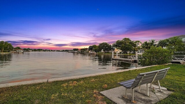 view of dock with a water view and a lawn