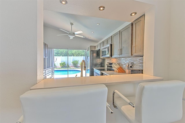 1666 Meadow Oak Ln, Tarpon Springs, FL 34689 - kitchen featuring appliances with stainless steel finishes, vaulted ceiling, tasteful backsplash, ceiling fan, and a peninsula