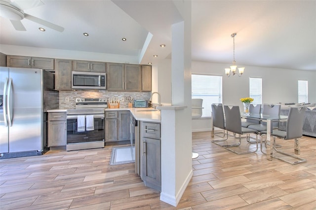 1666 Meadow Oak Ln, Tarpon Springs, FL 34689 - kitchen with appliances with stainless steel finishes, light countertops, a chandelier, backsplash, and light wood-style flooring
