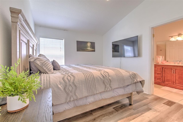 1666 Meadow Oak Ln, Tarpon Springs, FL 34689 - bedroom with vaulted ceiling, light wood-style flooring, and ensuite bathroom