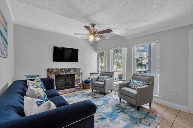337 Rex Pl Unit E, Madeira Beach, FL 33708 - living room featuring a stone fireplace, a textured ceiling, tile patterned flooring, a ceiling fan, and baseboards