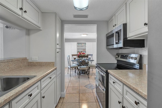 337 Rex Pl Unit E, Madeira Beach, FL 33708 - kitchen featuring appliances with stainless steel finishes, light countertops, white cabinetry, and a textured ceiling