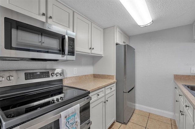 337 Rex Pl Unit E, Madeira Beach, FL 33708 - kitchen featuring appliances with stainless steel finishes, a textured ceiling, white cabinetry, baseboards, and light countertops
