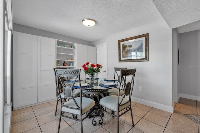 337 Rex Pl Unit E, Madeira Beach, FL 33708 - dining room with a textured ceiling, light tile patterned flooring, and baseboards