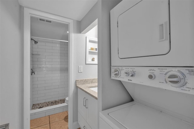 337 Rex Pl Unit E, Madeira Beach, FL 33708 - full bath with stacked washer / drying machine, a shower stall, toilet, vanity, and tile patterned flooring