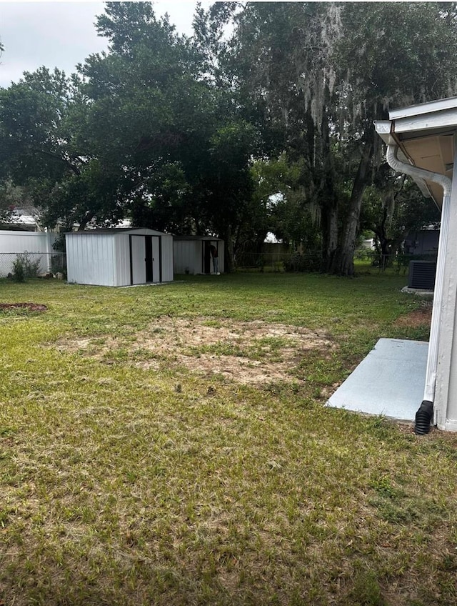 view of yard featuring a shed, an outdoor structure, and fence