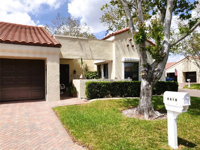 8810 41st St N, Pinellas Park, FL 33782 - mediterranean / spanish house featuring stucco siding, a garage, a tiled roof, and a front lawn
