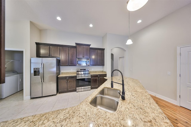 838 Vino Verde Cir, Brandon, FL 33511 - kitchen featuring arched walkways, a sink, appliances with stainless steel finishes, dark brown cabinets, and independent washer and dryer
