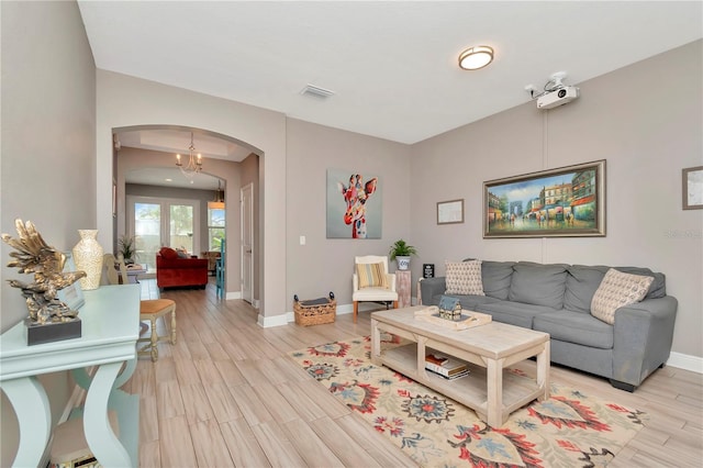 3408 W Bay Ave, Tampa, FL 33611 - living area featuring baseboards, visible vents, arched walkways, and light wood-style floors