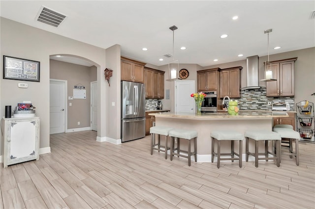 3408 W Bay Ave, Tampa, FL 33611 - kitchen with arched walkways, stainless steel appliances, visible vents, wall chimney exhaust hood, and a kitchen breakfast bar