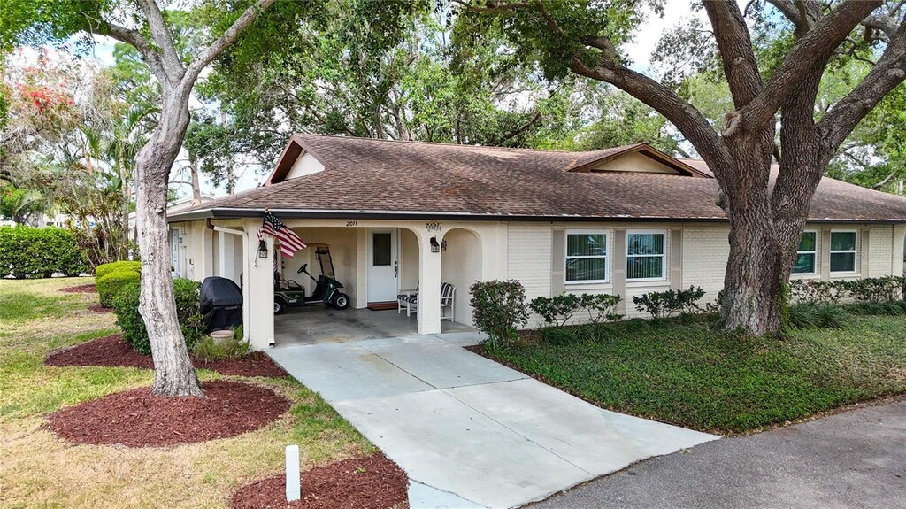 2011 Halidom Way Unit 0, Sun City Center, FL 33573 - ranch-style home featuring stucco siding, an attached carport, a front lawn, roof with shingles, and driveway