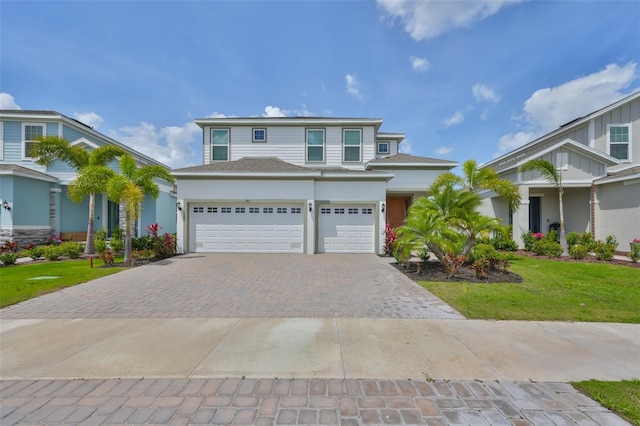 view of front facade featuring a shingled roof, a garage, a front lawn, and decorative driveway