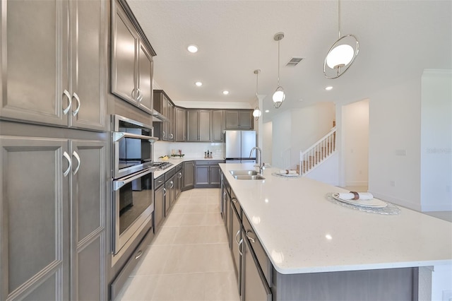 kitchen with a spacious island, a sink, appliances with stainless steel finishes, light tile patterned floors, and visible vents