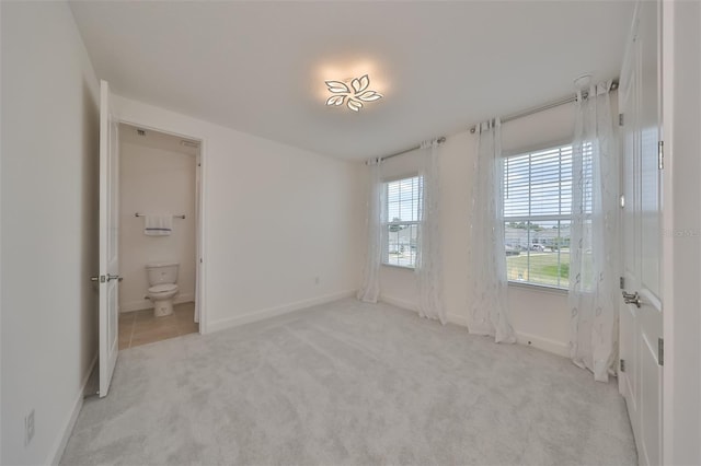 unfurnished bedroom with ensuite bathroom, baseboards, and carpet flooring