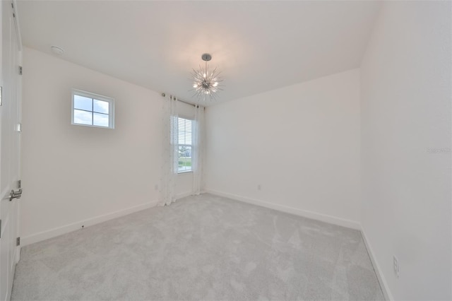 spare room with light colored carpet, baseboards, and a chandelier