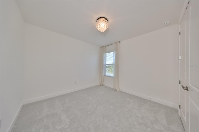 spare room featuring light carpet and baseboards