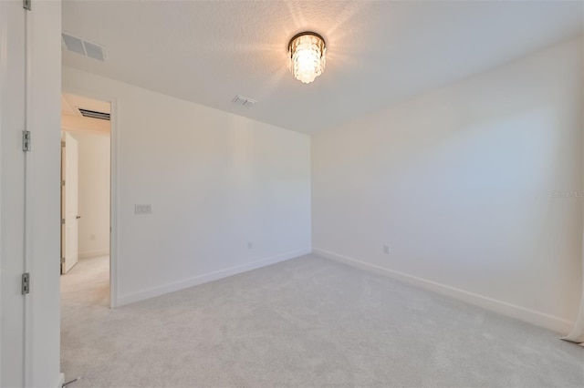 spare room with baseboards, visible vents, and light colored carpet