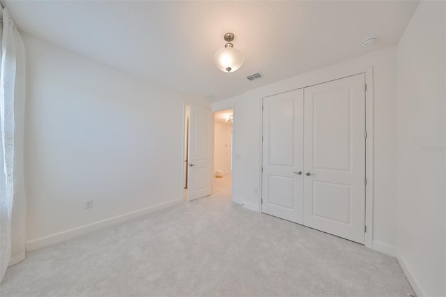 unfurnished bedroom with light carpet, baseboards, visible vents, and a closet